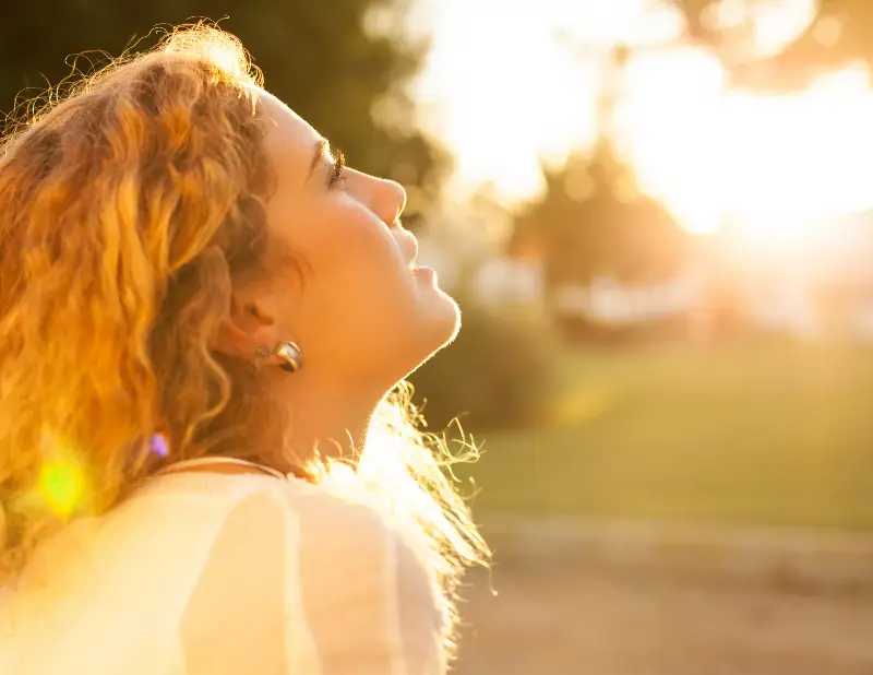 Woman looking content sat in the sunshine in a field